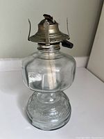 Front view of complete oil lamp showing glass body and brass burner
