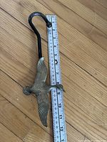 Full view of brass bird S-hook next to ruler showing approx 12 in length