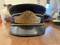 Front view showing brass M&S C Ry CONDUCTOR badge and cracked leather visor