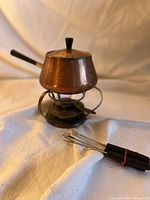 Full view of copper fondue pot on stand with forks