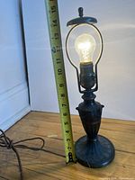 Full lamp with lit bulb and tape measure showing height