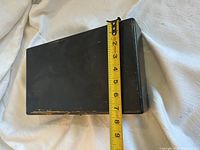 black hard case short side with measuring tape showing height