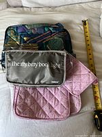 Overall view of tote, gray book light pouch, pink quilted pouches, measuring tape visible