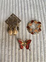 Front view of all three brooches on fabric background