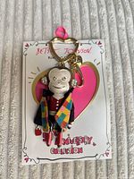 Front of monkey keychain on backing card, showing heart ring, lobster clasp, multicolor coat, rhinestone ears
