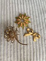 Front view of three brooches on fabric surface