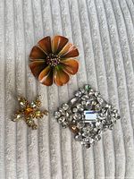 Three brooches arranged on fabric showing fronts