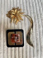 Front view of three brooches displaying designs and finishes