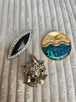 Front view of all three brooches showing styles, colours and materials