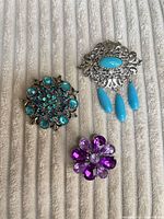 Front view of all three brooches showing design and colors