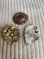 Front view of three brooches showing designs and stones