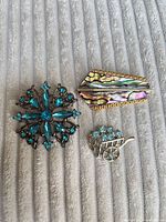 Front view of all three brooches on fabric background