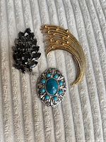 Front view of three brooches showing design and colours