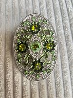 Front view of oval buckle showing silver filigree design and rhinestones