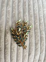 Front view of gold-tone leaf brooch with green enamel leaves