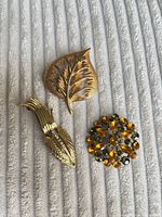 Front view of all three gold-tone brooches on fabric background