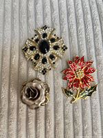 Front view of three brooches displaying designs and colours