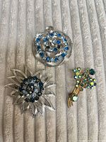 Group shot of three rhinestone brooches on fabric background