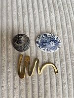 All three brooches side by side on fabric surface