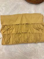 Folded mustard yellow cashmere scarf showing fringe detail