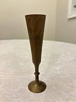 full view of brass bud vase showing shape, patina and engraving