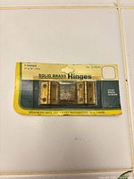 Front of retail card showing four brass hinges and branding