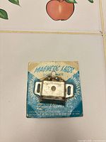 Front view of Door-Mate magnetic latch on original card