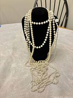 Necklace draped on black display bust showing length and pearl detail