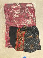 Both scarves overall, packaged red-pink scarf beneath black paisley scarf