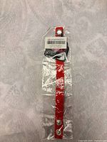 Sealed red faux leather bracelet with tag showing brand and barcode, full view including snaps