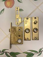 front view of mortise lock body, strike plate, two escutcheon plates