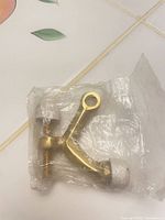 Door stopper in sealed bag showing brass body, rubber tip, mounting screw