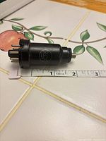 Side view of RCA 6J7 tube showing logo, top cap, seven pins and ruler for scale