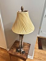 Full view of lamp with pleated shade on small table