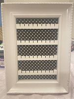 Front view showing white beaded frame, four slotted rows, polka dot backing