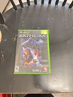 Front view of Zathura Xbox game case on table