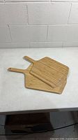 Two bamboo pizza boards stacked showing handle side