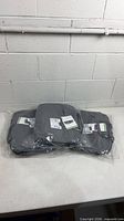 Three sealed grey Lenovo laptop bags laid side by side