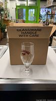 Closed cardboard box marked Glassware Handle With Care beside one Allagash glass