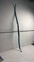 Full view of unstrung green recurve bow
