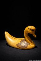 Full side view of wooden swan sculpture on dark background