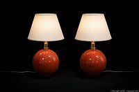 Pair of matching ceramic globe lamps with shades on black background