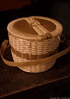 Front angled view showing wicker weave, leather strap accents, brass handle, shoulder strap attached