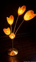 Full view of floor lamp showing five amber tulip shades, brass-tone stems, round base, power cord