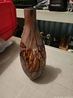 Full view of marbled amber and black glass vase