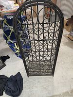 Full front view of arched cast iron wine rack with scrollwork detailing