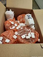 Box opened showing bubble-wrapped items, four larger round wrapped shapes and four smaller white-wrapped pieces