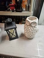 ceramic owl lantern and metal lantern side by side