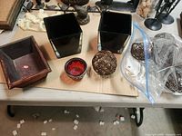 overall shot showing all items: metal spheres, black glass containers, red votive, wood tray