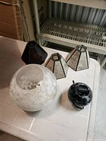 Top view of frosted globe shade, three hexagonal glass shades, part of black metal component